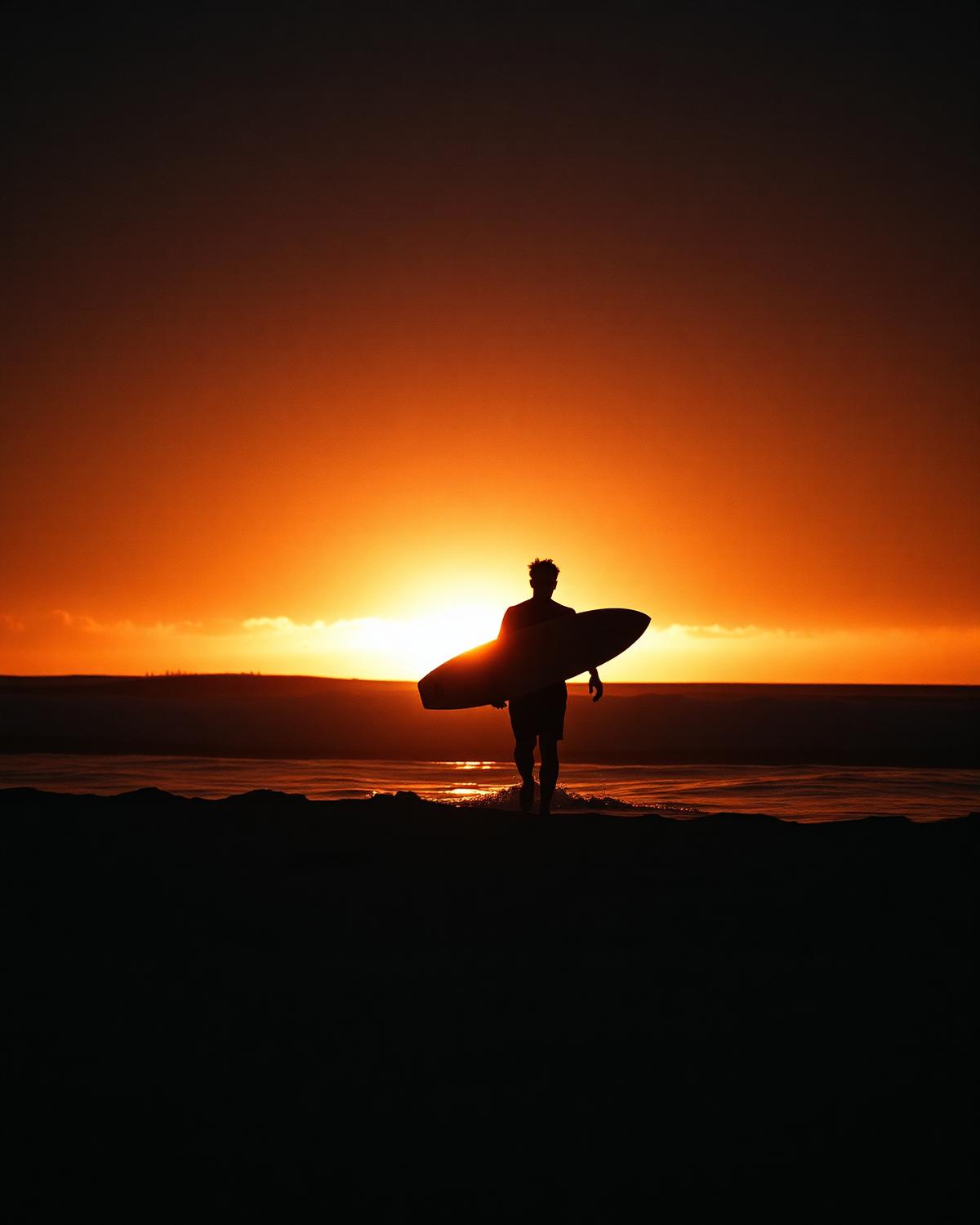 Surfista saindo do mar ao nascer do sol